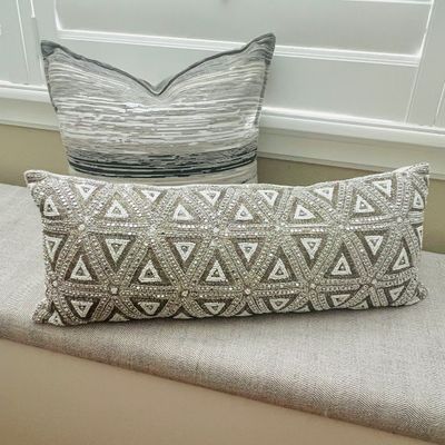 Sale Photo Thumbnail #19: Pair of decorative throw pillows, including a long lumbar pillow featuring an intricate beaded geometric triangle pattern and a square pillow with a neutral textured stripe design.