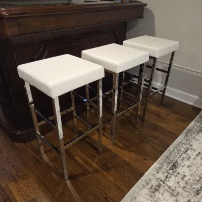 Sale Photo Thumbnail #67: Set of three contemporary backless barstools featuring white upholstered cushioned seats and polished chrome metal frames.