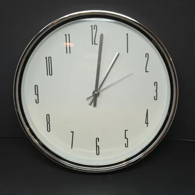Sale Photo Thumbnail #64: Modern round wall clock featuring a chrome frame, white face, and elongated black numerals.
