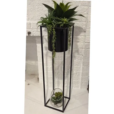 Sale Photo Thumbnail #82: Modern tall black metal plant stand featuring an inset cylindrical planter filled with faux succulents, along with a small glass terrarium resting on the lower base.