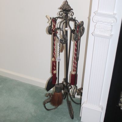 Sale Photo Thumbnail #18: Ornate wrought iron fireplace tool set featuring decorative red tassels and a fleur-de-lis finial.