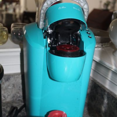 Sale Photo Thumbnail #94: Keurig single-serve coffee maker in a vibrant turquoise blue finish, shown with the pod chamber open.