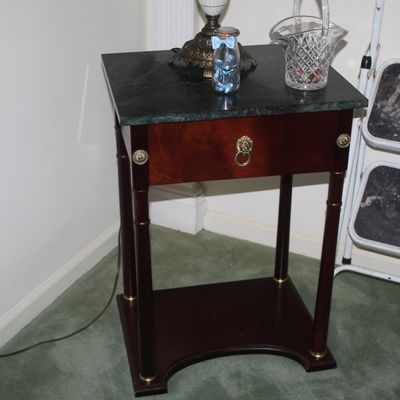 Sale Photo Thumbnail #63: Neoclassical-style mahogany side table featuring a dark green marble top, a single drawer with a brass lion head pull, and a lower shelf.