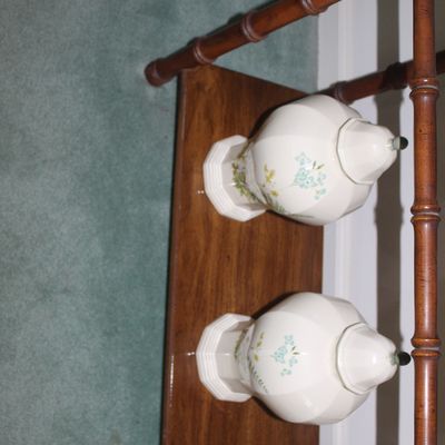 Sale Photo Thumbnail #13: Pair of vintage white ceramic ginger jars with delicate blue floral motifs, displayed on a wooden shelf with faux-bamboo detailing.