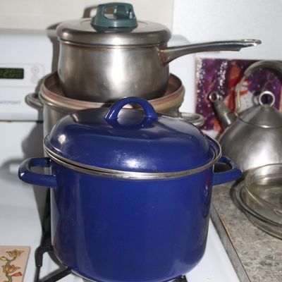 Sale Photo Thumbnail #97: Vintage blue enamel stockpot with lid, shown alongside stainless steel cookware and a tea kettle on a stovetop.