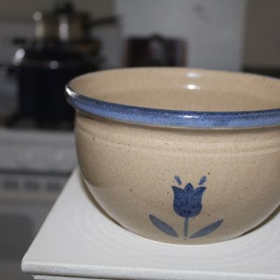 Sale Photo Thumbnail #91: Vintage stoneware mixing bowl featuring a hand-painted blue tulip motif and a matching blue rim glaze.