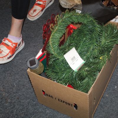 Sale Photo Thumbnail #57: Cardboard box filled with holiday decorations, including artificial green pine garland and a red decorative piece.