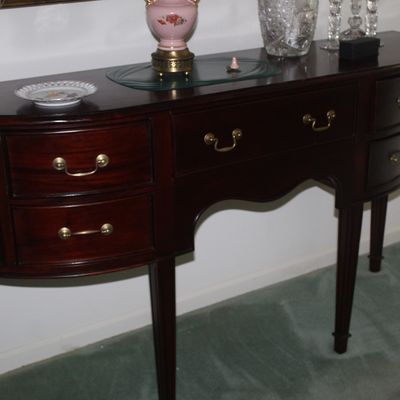 Sale Photo Thumbnail #67: Hepplewhite-style mahogany demi-lune sideboard featuring brass bail pulls, tapered legs, and a central drawer flanked by curved side drawers.