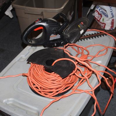 Sale Photo Thumbnail #55: Black & Decker electric hedge trimmer paired with a long orange extension cord on a plastic reel.