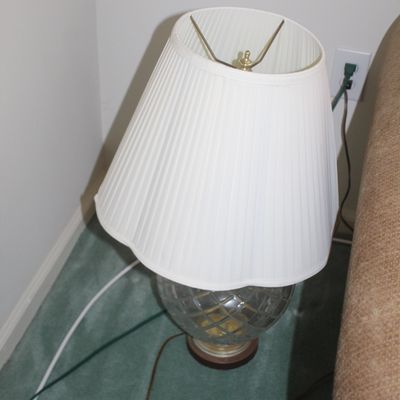 Sale Photo Thumbnail #32: Vintage table lamp featuring a cut glass globe base with a brass-finished pedestal and a white pleated fabric shade.