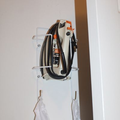 Sale Photo Thumbnail #127: Vintage General Electric steam iron stored in a white wire wall-mounted holder.