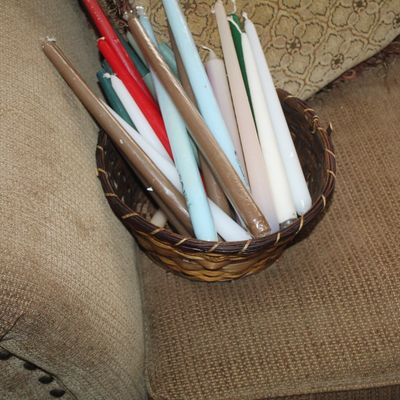 Sale Photo Thumbnail #33: Assorted taper candles in various colors, including red, blue, white, and brown, presented in a small woven basket.