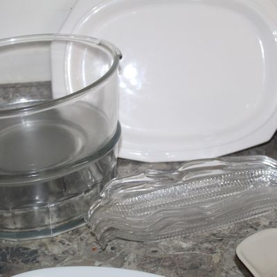Sale Photo Thumbnail #103: Assorted kitchenware including a stack of clear glass bowls, a white ceramic platter, and a set of clear glass corn-on-the-cob dishes.