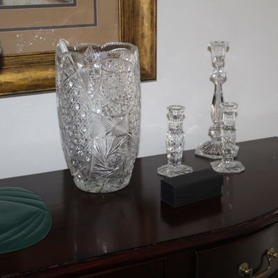 Sale Photo Thumbnail #66: American Brilliant Period cut glass vase with intricate pinwheel and star patterns, displayed alongside three coordinating cut glass candlesticks of varying heights.