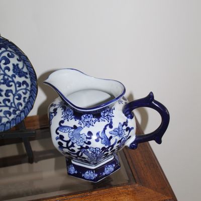 Sale Photo Thumbnail #8: Vintage blue and white porcelain pitcher featuring intricate floral and scroll patterns with a solid blue handle and base.
