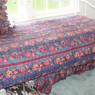Sale Photo Thumbnail #74: White metal daybed featuring a matching floral comforter, pillow sham, and bed skirt in shades of blue, red, and gold.