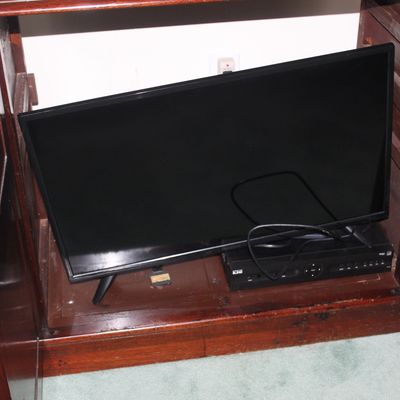 Sale Photo Thumbnail #34: Flat-screen television and a digital receiver box, shown resting inside a dark wood cabinet.