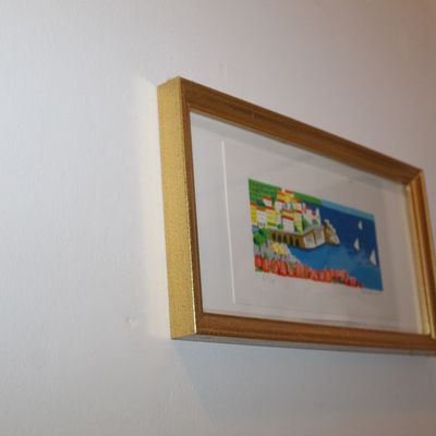 Sale Photo Thumbnail #125: Framed miniature art print depicting a colorful coastal town with sailboats, housed in a matted gold-finished frame.