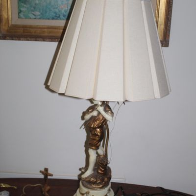 Sale Photo Thumbnail #106: Vintage table lamp featuring a sculpted figure of a boy playing a flute, finished in gold and cream tones, topped with a pleated fabric shade.