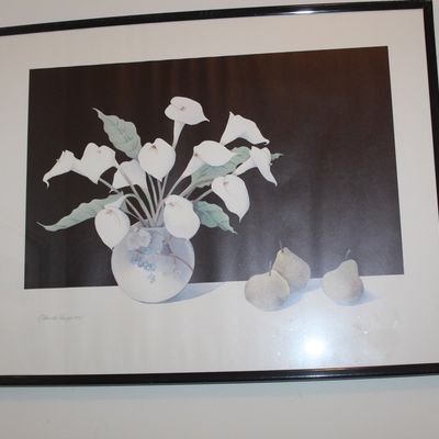 Sale Photo Thumbnail #126: Framed still life print depicting white calla lilies in a round vase alongside three pears, set against a dark background in a simple black frame.