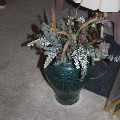 Sale Photo Thumbnail #110: Dark green ceramic urn-style vase featuring ribbed and floral embossed details, filled with an arrangement of faux eucalyptus, white blossoms, and dried wheat stalks.