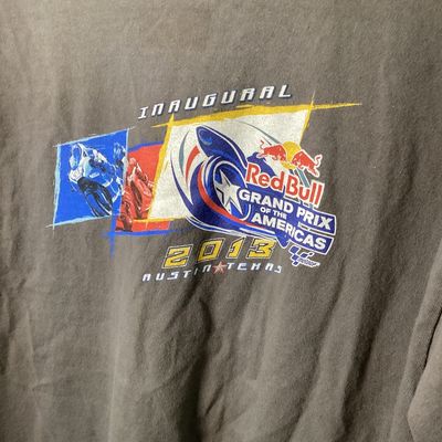 Sale Photo Thumbnail #525: Short sleeve gray T-shirt commemorating the Inaugural Red Bull Grand Prix of the Americas held in 2013 at the Circuit of the Americas in Austin, Texas. Features bold front and back motorcycle racing graphics with MotoGP logos.

- Size: Large (L / G)
- Mat