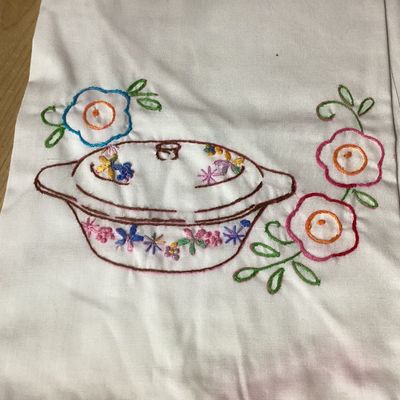 Sale Photo Thumbnail #342: Set of 4 vintage white cotton tea towels featuring colorful hand-embroidered kitchen and dining motifs including teapots, teacups, utensils, a covered dish, and floral accents. Each towel is finished along the bottom edge with hand-crocheted trim in vario