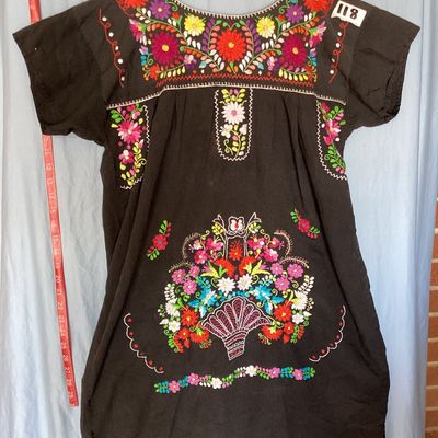 Sale Photo Thumbnail #392: Black short-sleeve embroidered Mexican huipil tunic dress featuring colorful floral embroidery across the neckline, chest, and front lower panel. Features a scoop neckline with stitch details and side vents at the hem. Measures approximately 35 inches in 