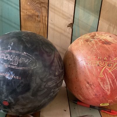 Sale Photo Thumbnail #534: Pair of drilled bowling balls. Includes:
1. Columbia 300 "Freeze" bowling ball in dark swirl finish, made in USA, 
2. Brunswick "Lethal Revolver" bowling ball in orange swirl finish, featuring USBC certification stamp GDC31053.

Condition: Used condition 