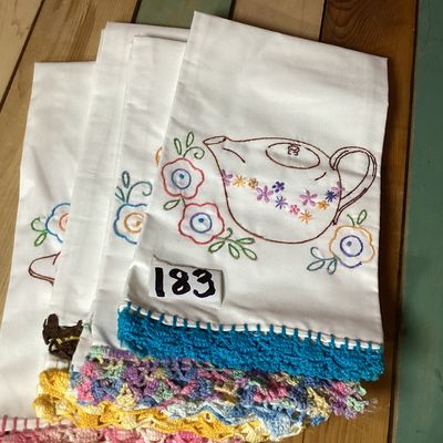 Sale Photo Thumbnail #337: Set of 4 vintage white cotton tea towels featuring colorful hand-embroidered kitchen and dining motifs including teapots, teacups, utensils, a covered dish, and floral accents. Each towel is finished along the bottom edge with hand-crocheted trim in vario