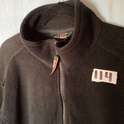 Sale Photo Thumbnail #414: L.L. Bean black full-zip fleece jacket featuring a high collar, hand pockets, and an internal cinch waist toggle drawcord for an adjustable fit. Front measures approximately 28 inches in length. In good pre-owned condition with light signs of wear consist