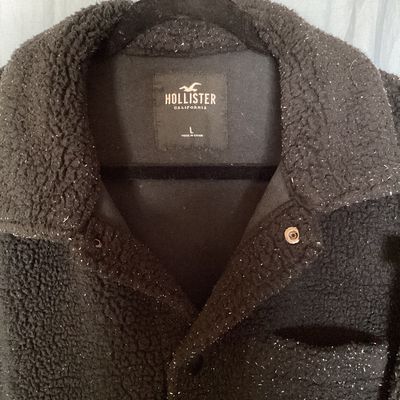 Sale Photo Thumbnail #424: Hollister California fleece sherpa jacket in men's size Large. Features a dark black fabric with white flecked detailing throughout, front snap/button closure, chest patch pocket, side hand pockets, and a collared neckline. Appears to be in good pre-owned