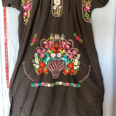 Sale Photo Thumbnail #394: Black short-sleeve embroidered Mexican huipil tunic dress featuring colorful floral embroidery across the neckline, chest, and front lower panel. Features a scoop neckline with stitch details and side vents at the hem. Measures approximately 35 inches in 
