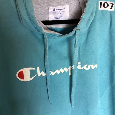 Sale Photo Thumbnail #452: Champion Authentic Athleticwear men's pullover hooded sweatshirt in teal/light blue featuring white script logo printed on front, drawstring hood with gray lining, and front kangaroo pocket. Size XLT (Extra Large Tall). Made in Pakistan. Measures approxim