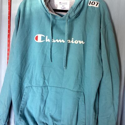 Sale Photo Thumbnail #450: Champion Authentic Athleticwear men's pullover hooded sweatshirt in teal/light blue featuring white script logo printed on front, drawstring hood with gray lining, and front kangaroo pocket. Size XLT (Extra Large Tall). Made in Pakistan. Measures approxim