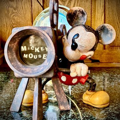 Sale Photo Thumbnail #81: Vintage Mickey Mouse movie camera desk clock, featuring a distressed bronze-style finish with Mickey operating a classic film camera.