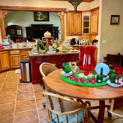 Sale Photo Thumbnail #174: Round wooden dining table with cane-back chairs, featuring a festive holiday centerpiece with red and green glassware, set in a spacious kitchen with oak cabinetry.
