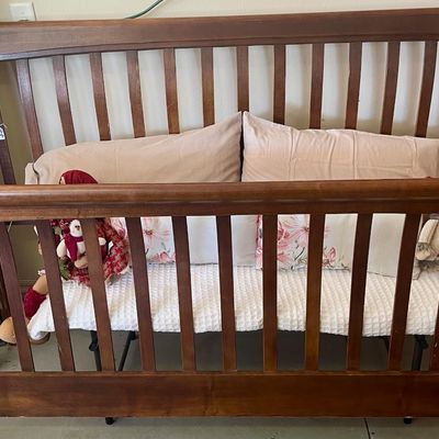Sale Photo Thumbnail #65: King size wooden sleigh bed with a dark cherry finish, styled with pillows, a white waffle-weave blanket, and plush toys.
