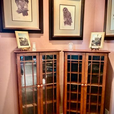Sale Photo Thumbnail #99: Pair of Mission-style oak media or display cabinets with glass-paneled doors, shown beneath framed bird prints.