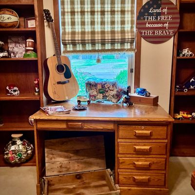 Sale Photo Thumbnail #58: Oak single-pedestal desk with four drawers, shown with an acoustic guitar, a vintage wooden crate, and various collectibles.