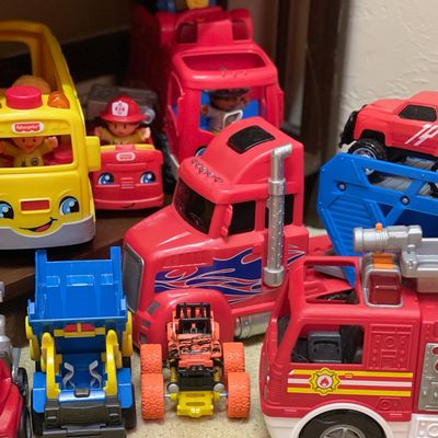 Sale Photo Thumbnail #104: Collection of children's toy vehicles, including a yellow Fisher-Price school bus, a red semi-truck with flame decals, and various fire trucks and construction vehicles.