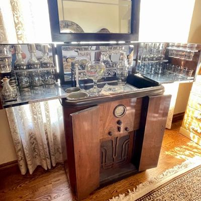 Sale Photo Thumbnail #3: Vintage Art Deco style radio bar cabinet in walnut, featuring a fold-out bar top with glassware, decanters, and a built-in radio receiver below.