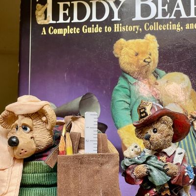 Sale Photo Thumbnail #212: Two vintage teddy bear figurines, including a Boyds Bears firefighter, displayed in front of a teddy bear collector's guide book.