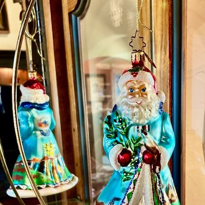 Sale Photo Thumbnail #218: Christopher Radko hand-painted glass Santa Claus ornament, featuring a blue and green robe with glitter accents, displayed on a brass-tone wire stand.