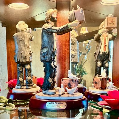 Sale Photo Thumbnail #219: Ron Lee "Watch the Birdie" limited edition clown figurine, featuring a hand-painted metal sculpture on a wooden base with a brass nameplate, displayed in a mirrored curio cabinet.