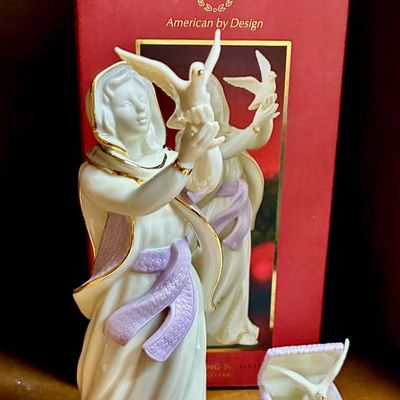 Sale Photo Thumbnail #207: Lenox porcelain figurine depicting a woman releasing a dove, featuring gold accents and a lavender sash, shown with its original box and a small matching basket accessory.