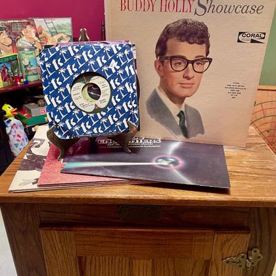 Sale Photo Thumbnail #32: Vintage vinyl records, including a Buddy Holly Showcase LP on Coral Records and a Ringo Starr 45 RPM single, displayed on a wooden cabinet.