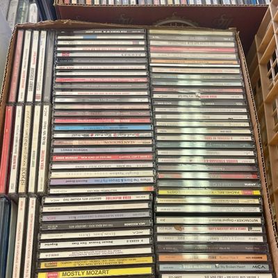 Sale Photo Thumbnail #235: Large collection of vintage music CDs in jewel cases, organized in cardboard storage boxes, featuring artists like Reba McEntire, Barbra Streisand, and Alan Jackson.