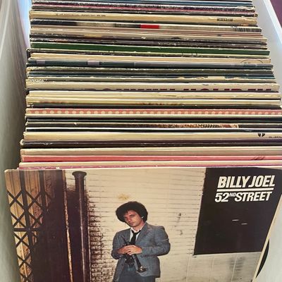 Sale Photo Thumbnail #69: Collection of vintage vinyl records in a plastic storage bin, featuring Billy Joel's "52nd Street" album at the front.