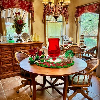 Sale Photo Thumbnail #9: Traditional round wooden dining table with barley twist legs, paired with rolling cane-back chairs and decorated with festive red and green glassware.